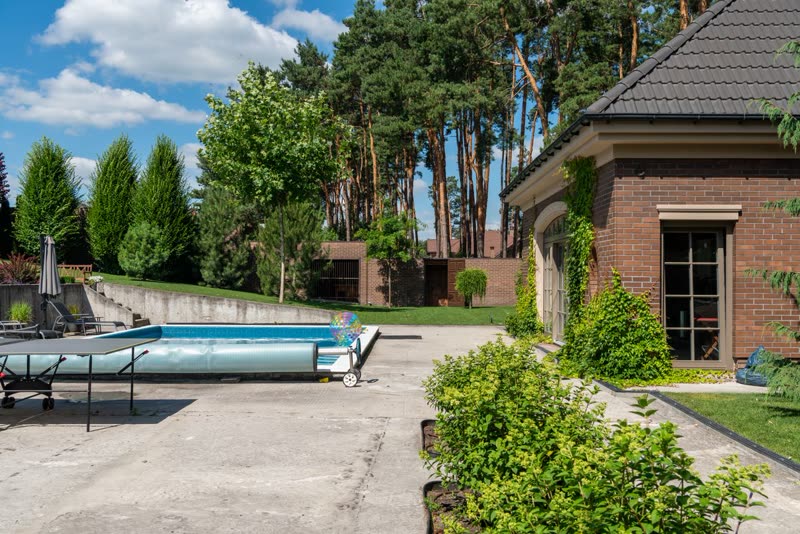 Concrete pool deck and patio beside a brick house