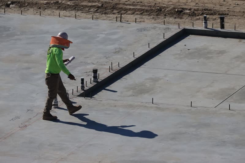 Worker walking across a freshly poured concrete slab inside its forms